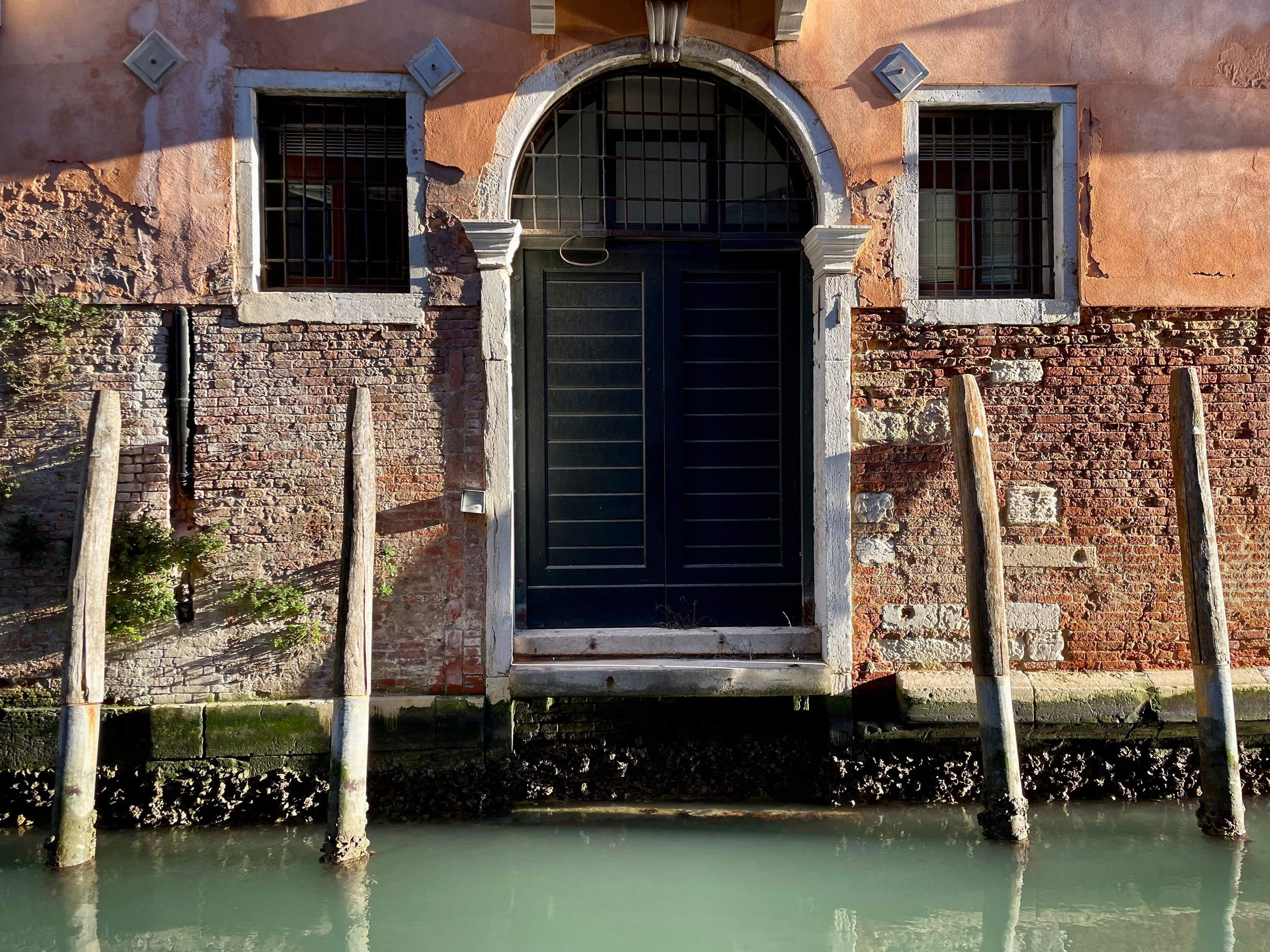 Wall with a door and 2 windows along the canal, in Venice, Italy.