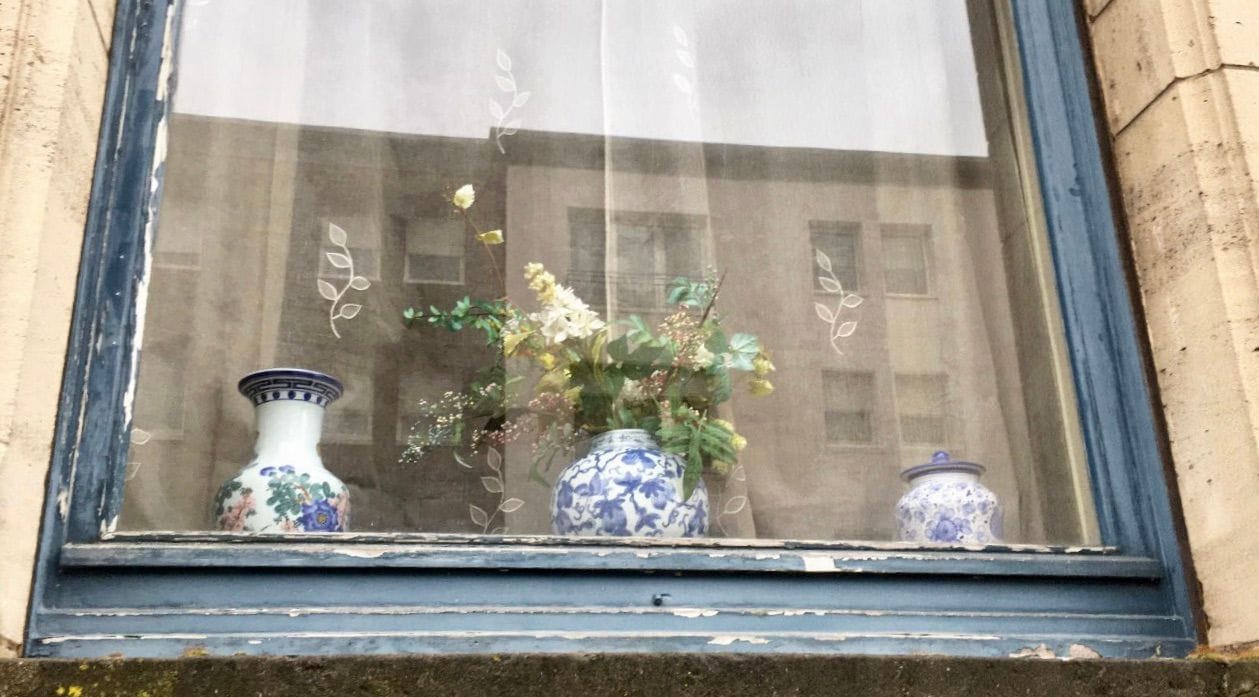 Blue window frame of a house with Chinese pottery, in Luxembourg.