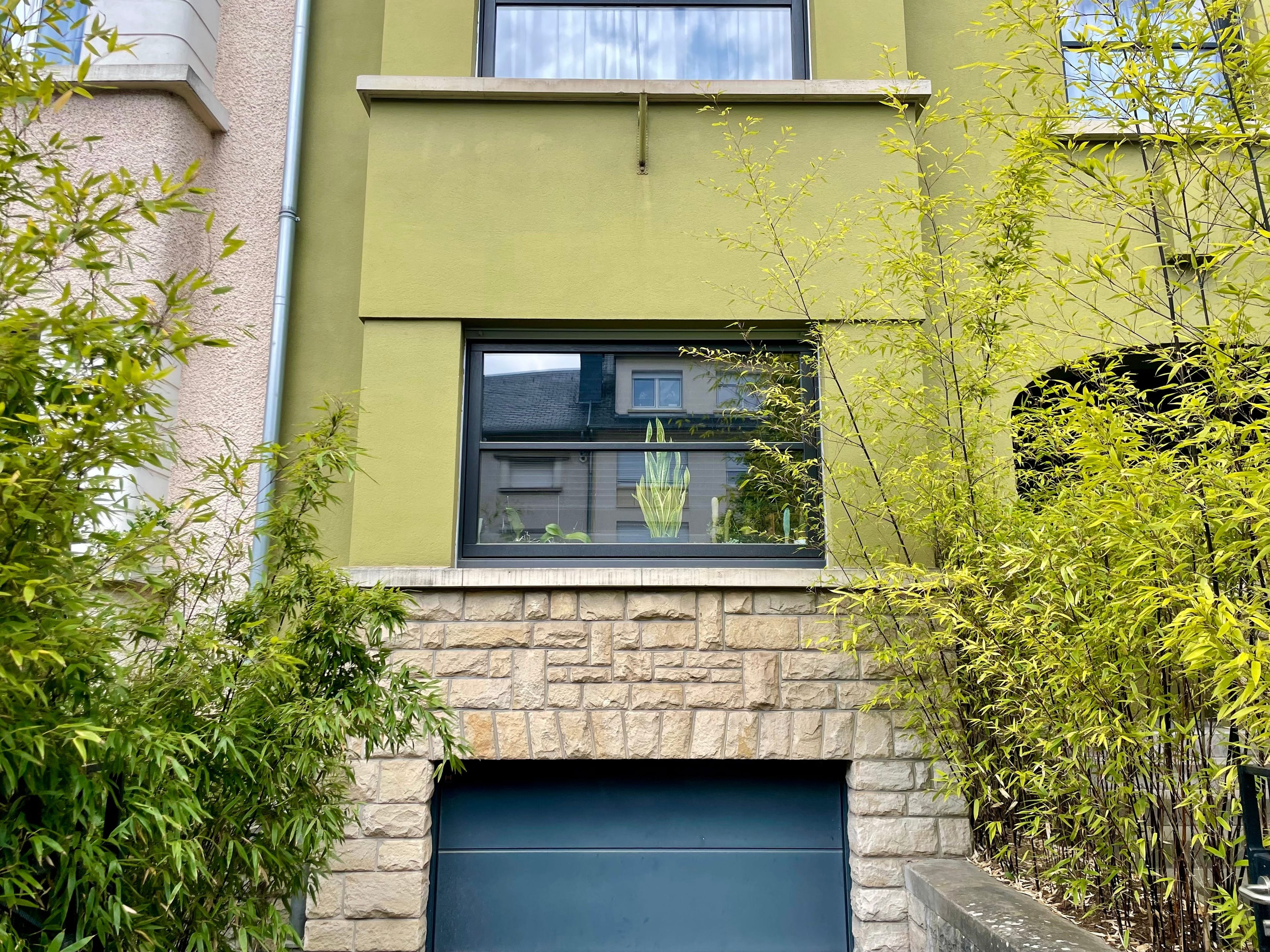 2 windows and a garage door of a light green house in Luxembourg.